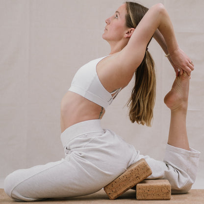 woman using two Noveme cork yoga blocks to assist king pigeon pose
