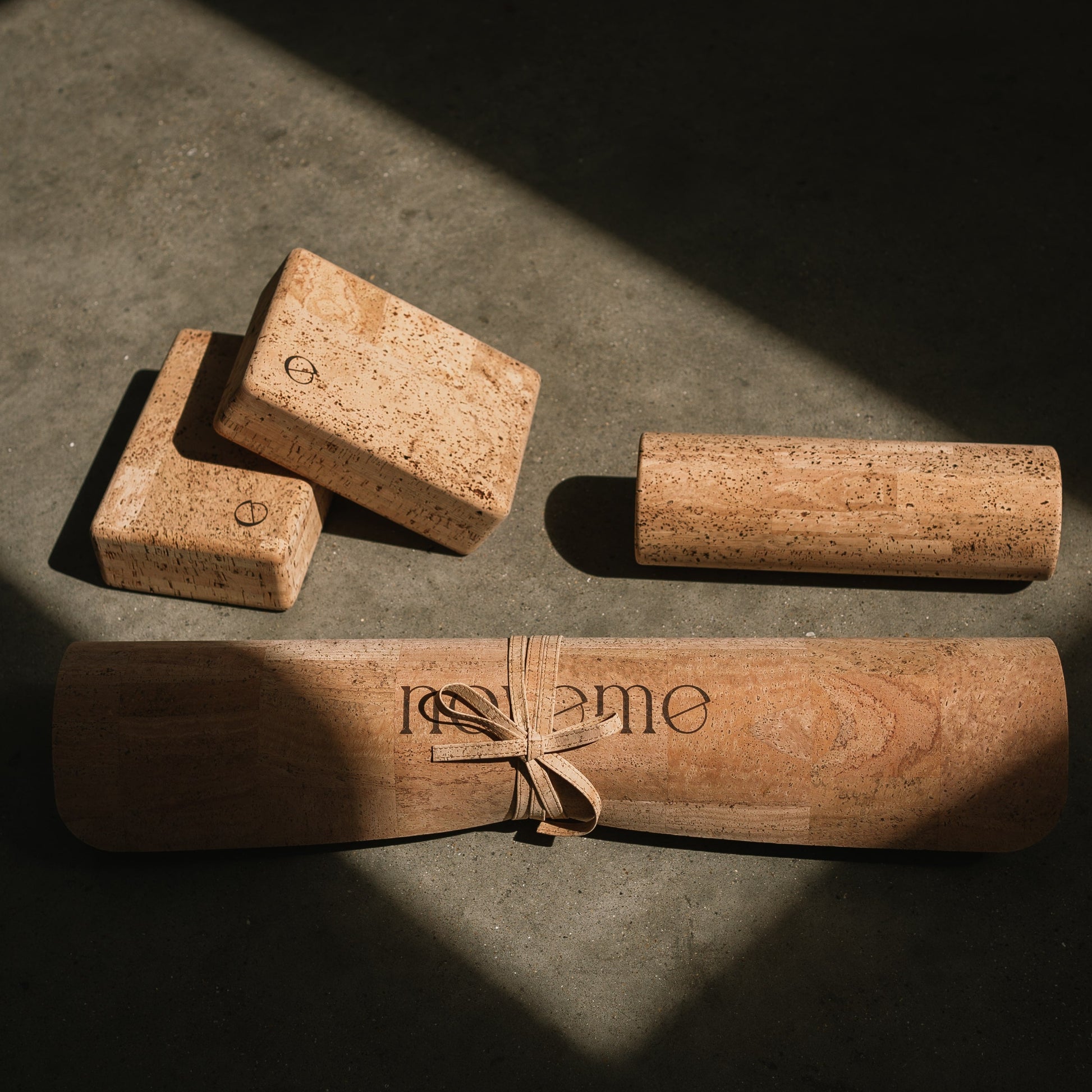A Noveme Cork Yoga Mat next to two Cork Yoga Blocks and a Roller
