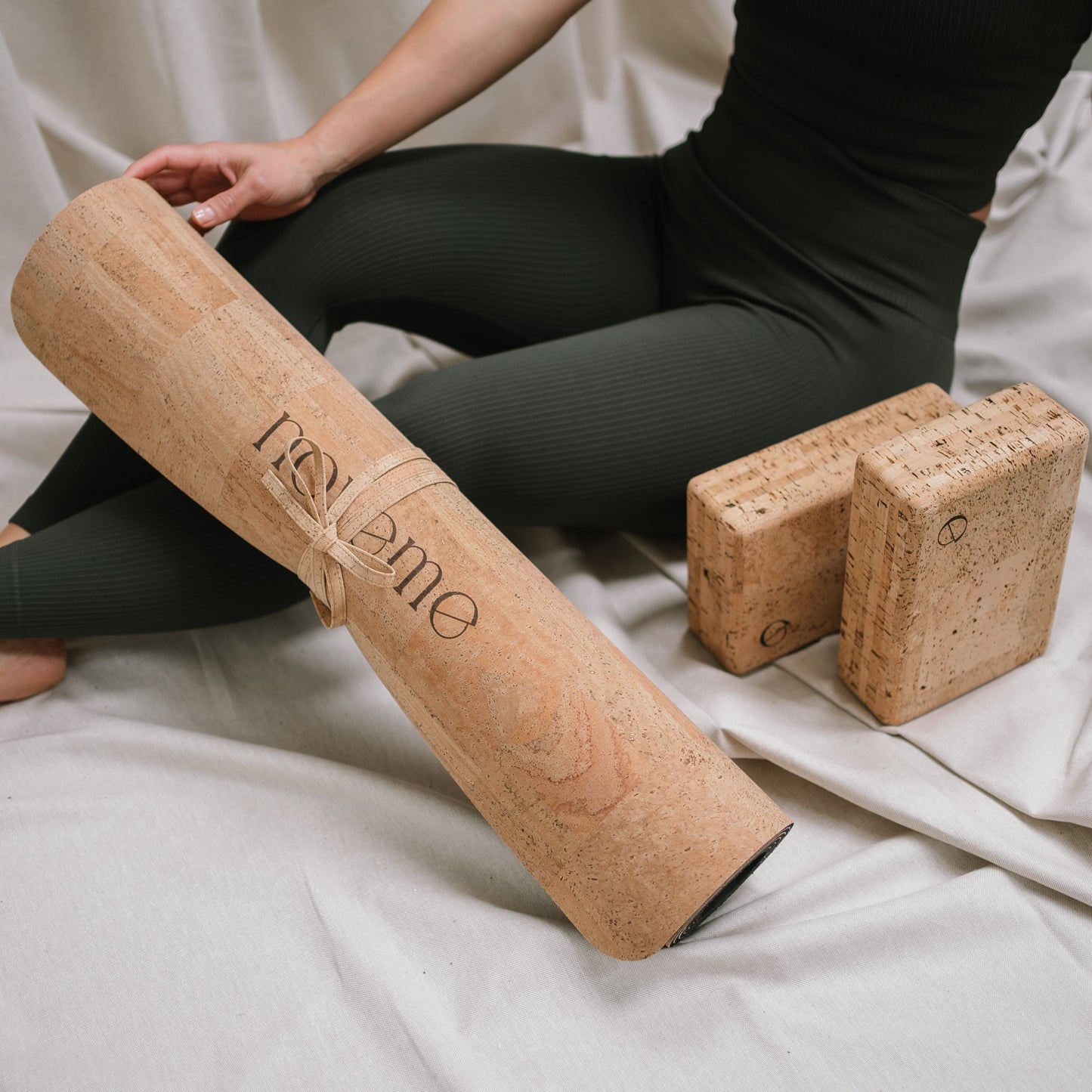 Yogi seated next to Noveme yoga mat and block set