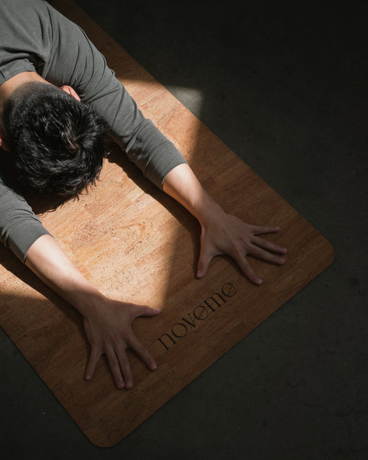 model doing child pose on Noveme natural cork yoga mat